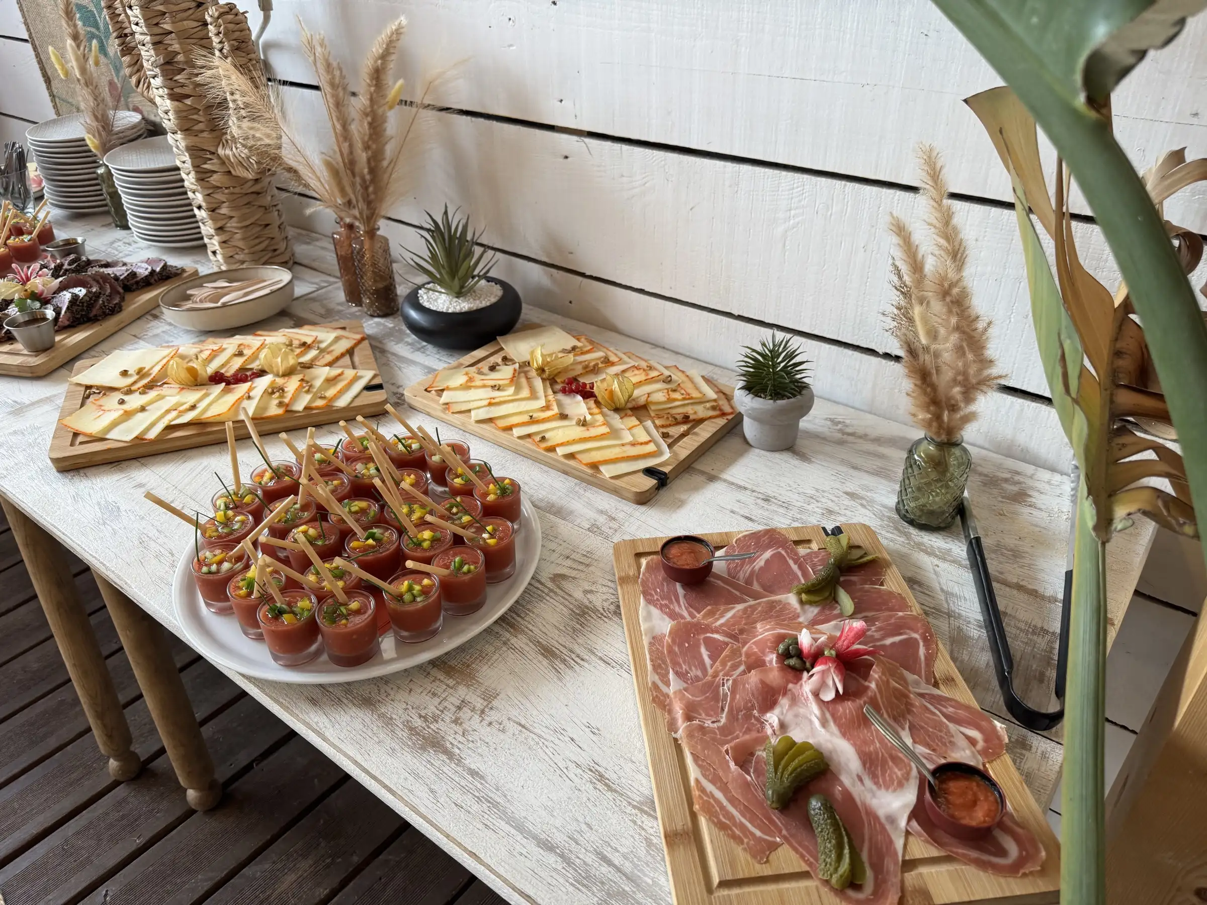 Buffet dressé en terrasse : verrines de gaspacho, planches de charcuterie et de fromages